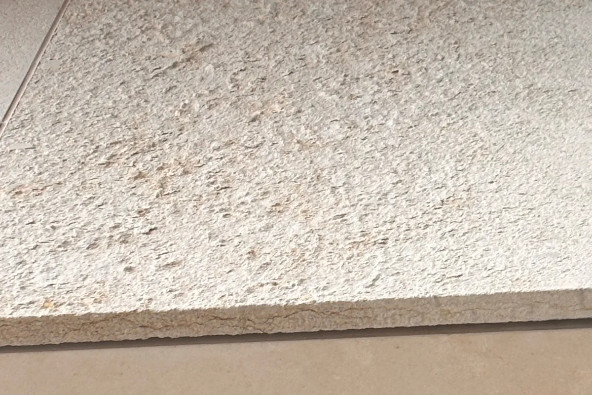 Duas placas de pedra lado a lado: uma soltando películas finas e outra com textura arenosa.