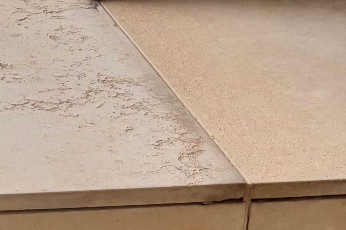 Borda de peça horizontal de pedra com textura granulada e finas camadas visíveis na espessura.