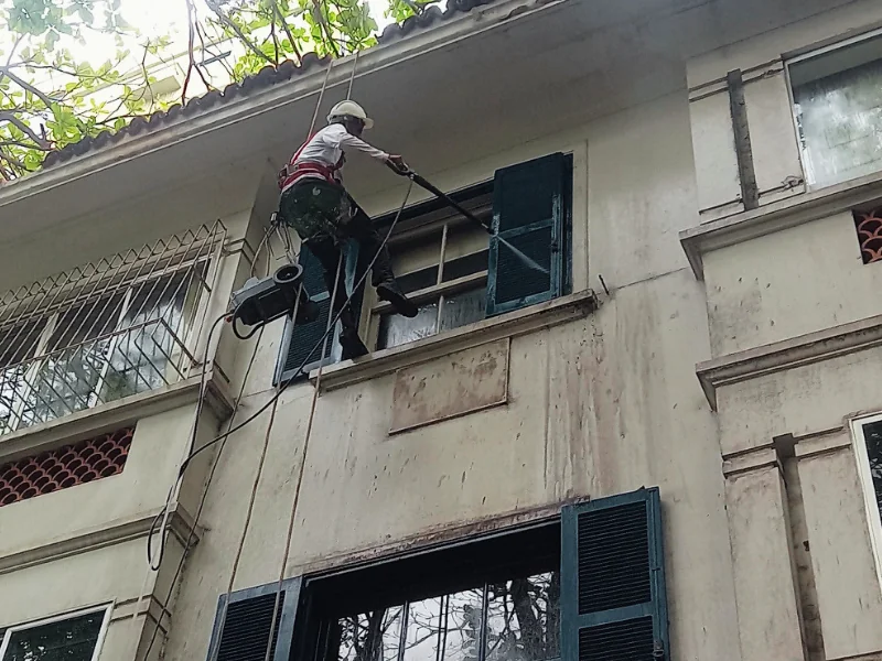 Limpeza técnica de fachada predial realizada por profissional em altura